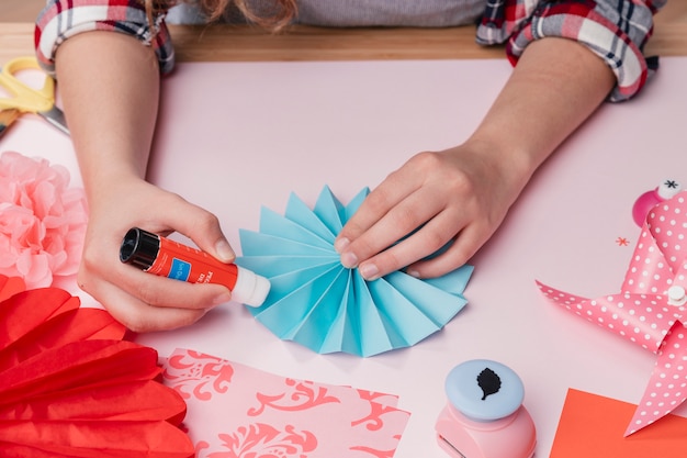 Free photo close-up of female artist sticking blue origami paper fan