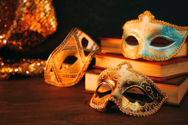 Close-up of female carnival mask with books on wooden desk