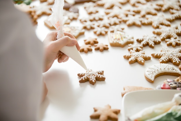 Free photo close up of female confectioner hands icing gingerbread stars