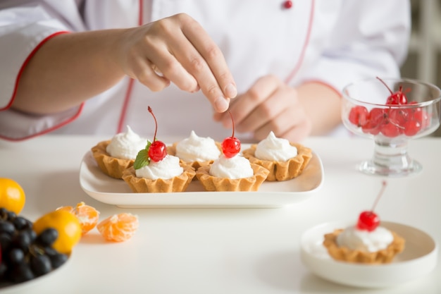 Free Photo close up of female confectioner hands topping custard tarts