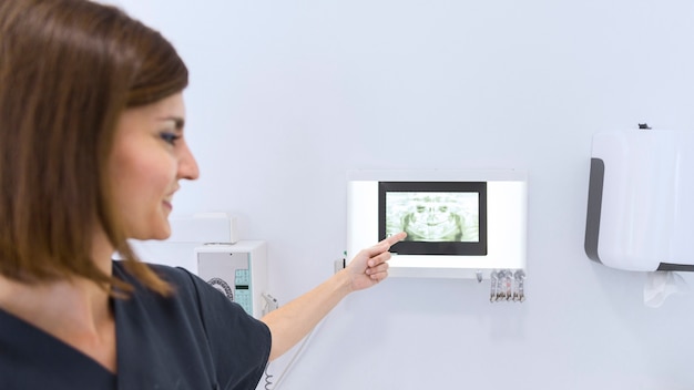 Free photo close-up of a female dentist pointing at teeth x-ray in clinic