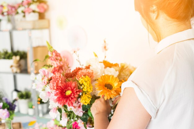 Close-up of female florist hand arranging colorful flowers