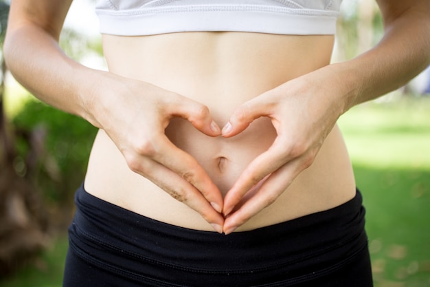 Free Photo close-up of female hands shaping heart on belly