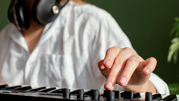 Free photo close-up of female musician with piano keyboard and headphones indoors