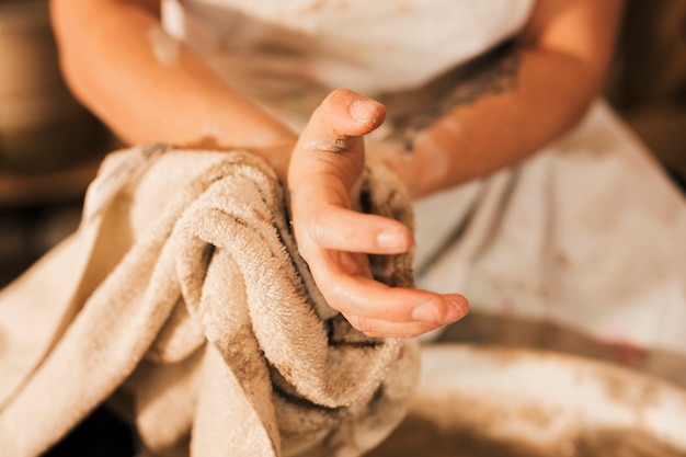 Free Photo close-up of female potter cleaning her hand with napkin