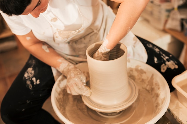 Free photo close-up of female potter's hand making earthen pot on pottery wheel