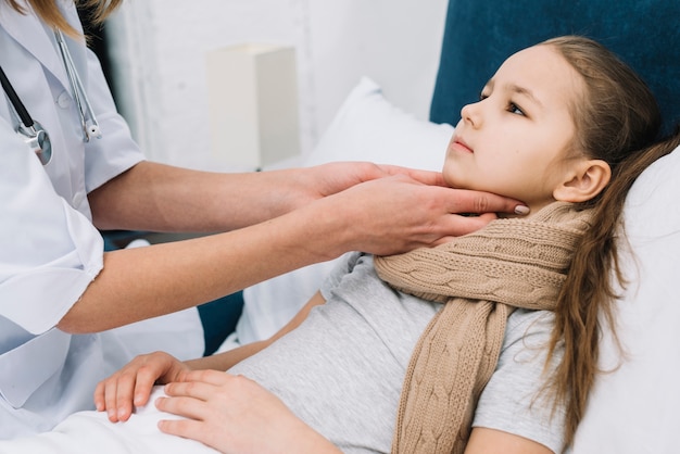 Free photo close-up of female's doctor hand checking the girl patient's throat and neck