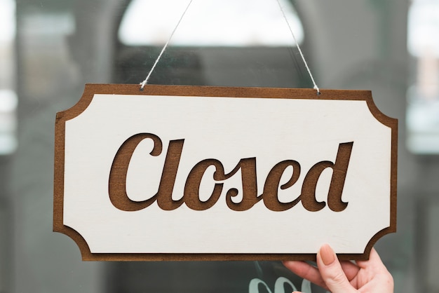 Free photo close-up of a female's hand holding closed tag on glass door