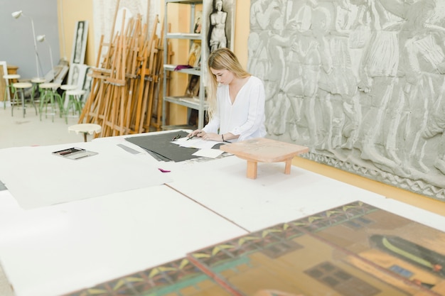 Free Photo close-up of female sketching on workbench over the table