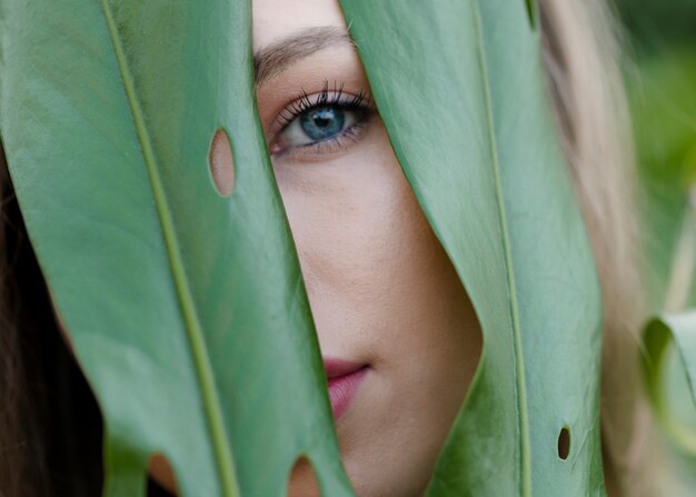 Free Photo close-up female watching through leaves