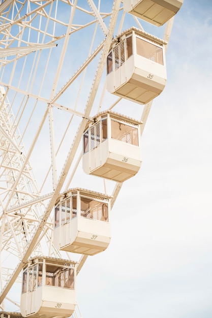 Free photo close-up of ferris wheel white cabins against blue sky