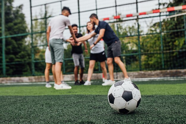 Close up of football ball  on green field.. Players going  to playing together..