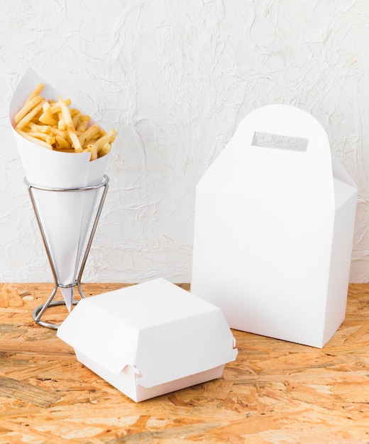 Free photo close-up of french fries and food parcel mock up on wooden desk