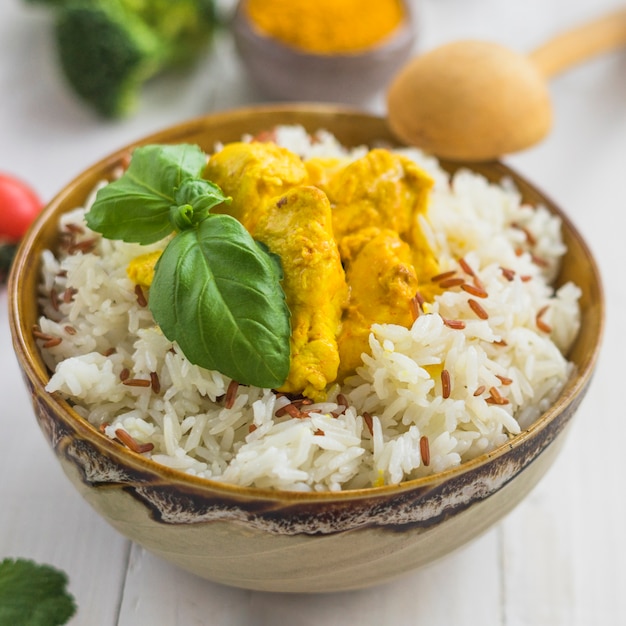 Free Photo close-up of fresh boiled rice; basil leaves and fried chicken in bowl with wooden spoon