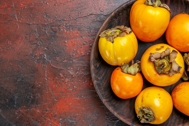 Close up of fresh organic natural yellow diospyros kaki on a brown plate d