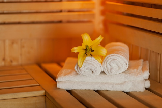 Free photo close up fresh towels and yellow lily in sauna