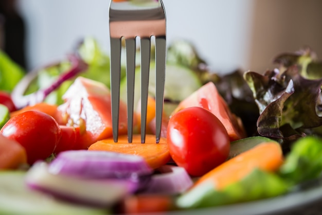 Close up of fresh vegetables salad in the bowl with rustic old wooden background. Healthy food concept.