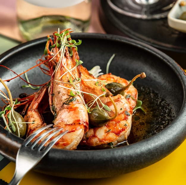 Close up of fried prawns garnished with pickles and fresh herbs