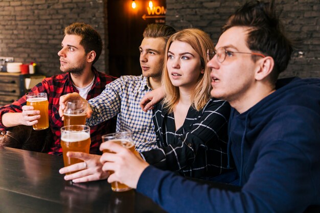 Close-up of friends holding the glasses of beer looking away