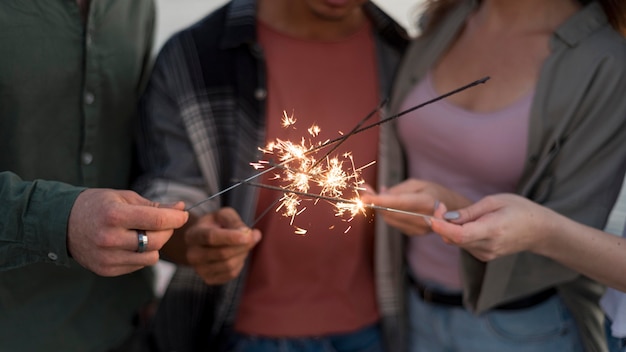 Free photo close-up friends holding sparkling fireworks