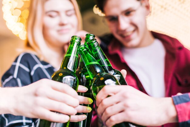 Close-up of friends toasting the green beer bottles