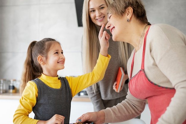 Close up on girl cooking with her mother and grandmother