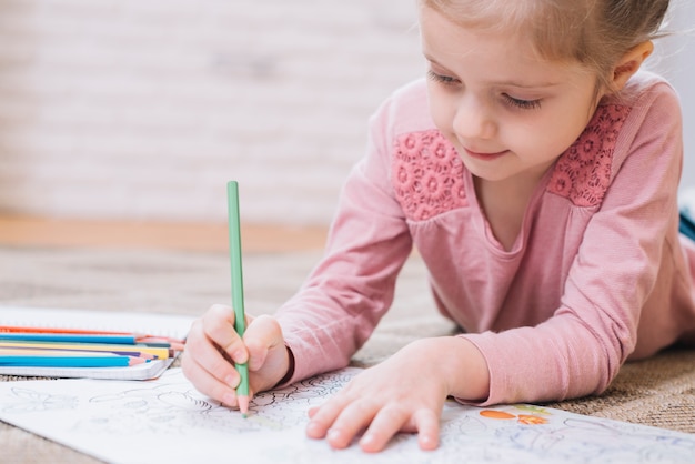 Close-up of a girl drawing in book with colored pencil