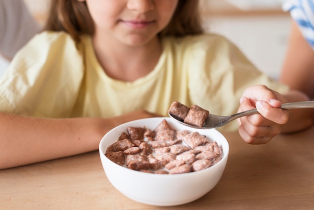 Close-up girl eating milk and cereals