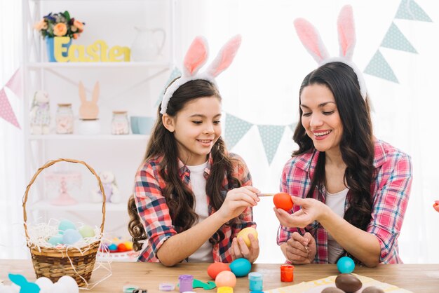 Close-up of girl and mother coloring eggs for easter at home