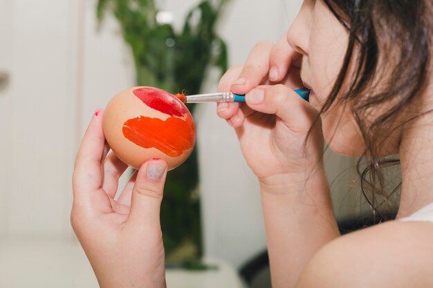 Close-up girl painting egg