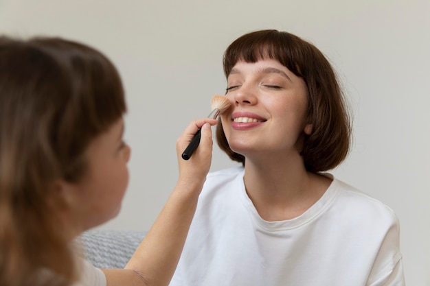 Close up girl putting make-up on mother