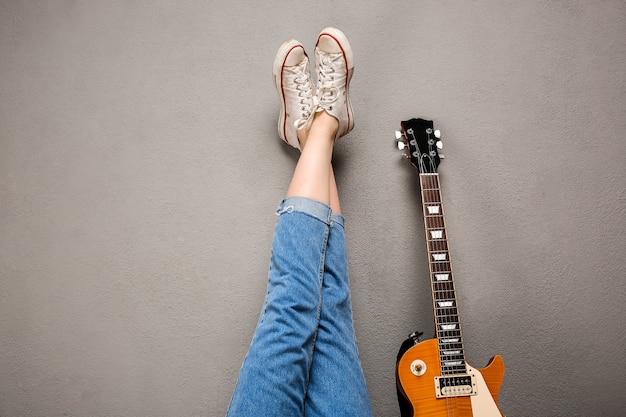 Free photo close up of girl's legs and guitar over grey background.