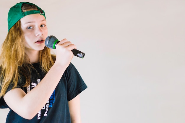 Free photo close-up of a girl singing song with microphone on colored background