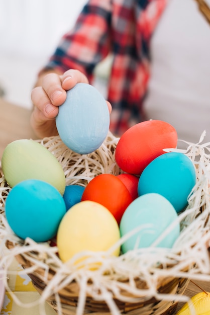 Close-up of a girl taking blue easter egg from the nest