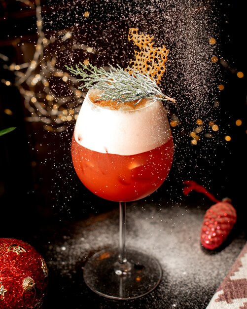 Close up of a glass of citrus cocktail garnished with pine leaves