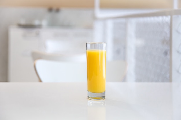 Close up of a glass of orange juice on a blurred light background of a cafe interior.