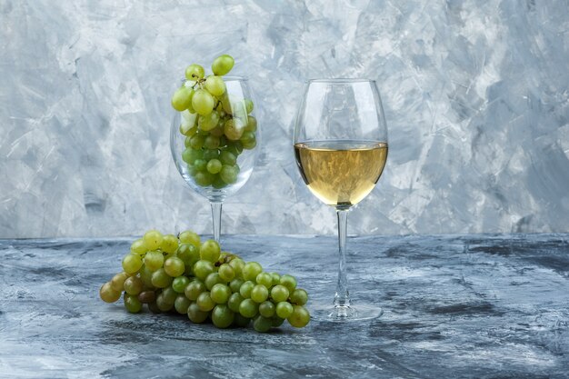 Close-up glass of white grapes with glass of whisky on dark and light blue marble background. horizontal