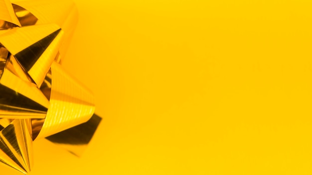 Free photo close-up of golden ribbon bow on yellow backdrop