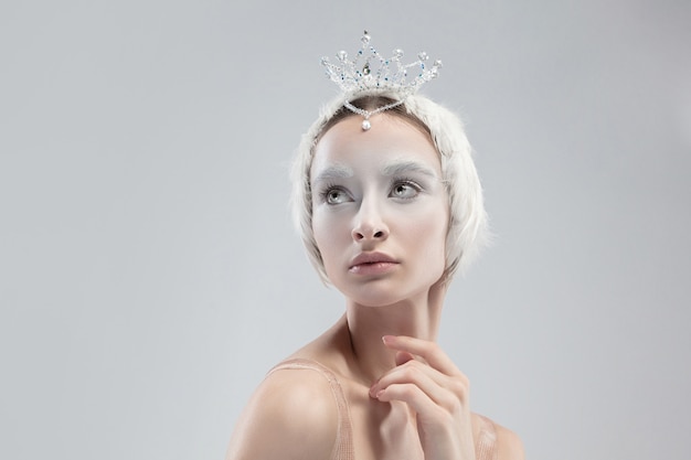 Close up of graceful classic ballerina on white studio background. Woman in tender clothes like a white swan character. The grace, artist, movement, action and motion concept. Looks weightless.