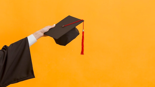 Free photo close up graduate student holding cap