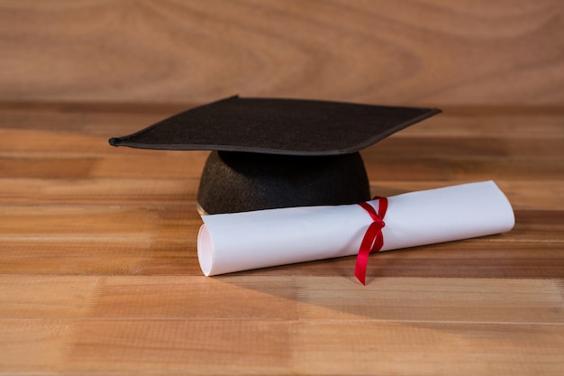 Close-up of graduation certificate with mortar board on a table