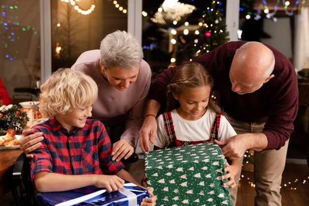 Close up on grandparents and kids opening gifts