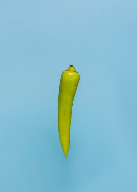 Close-up of a green chili pepper on blue surface