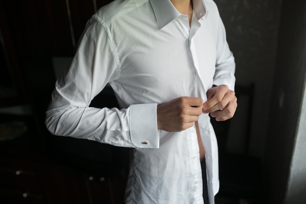 Free Photo close-up of groom buttoning his shirt