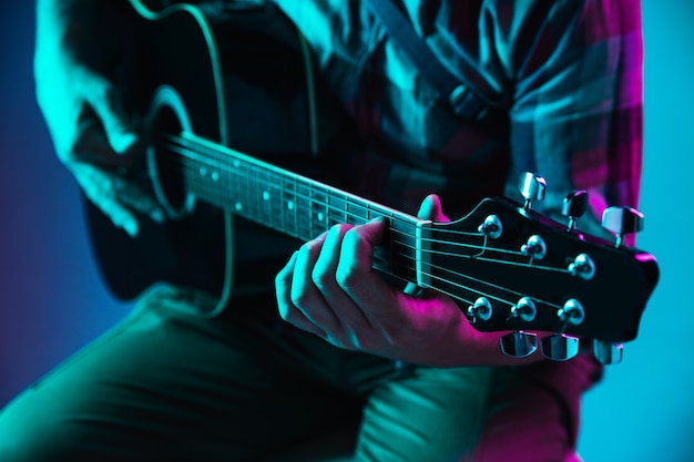 Close up of guitarist hand playing guitar, macro. Concept of advertising, hobby, music, festival, entertainment. Person improvising inspired. Copyspace to insert image or text. Colorful neon lighted.