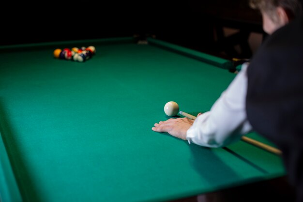 Close-up guy ready to hit white pool ball 