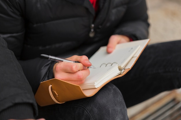 Free Photo close-up guy writing in notebook