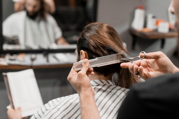 Close-up of a hairdresser's hand cutting male client's hair with scissors