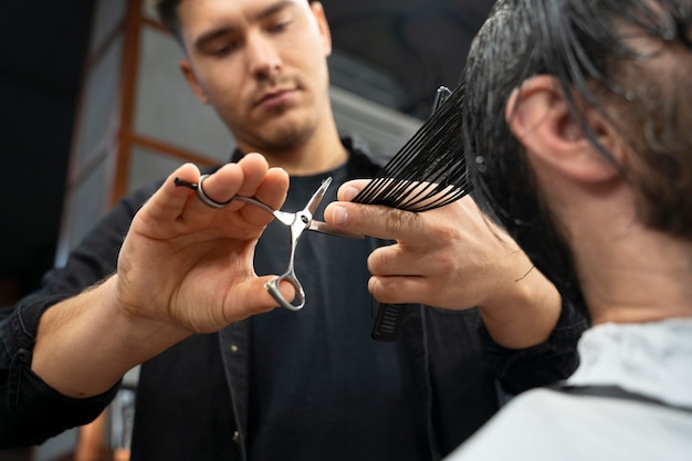 Free photo close up hairdresser using scissors