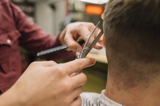 Close-up hairstylist giving a haircut to a client